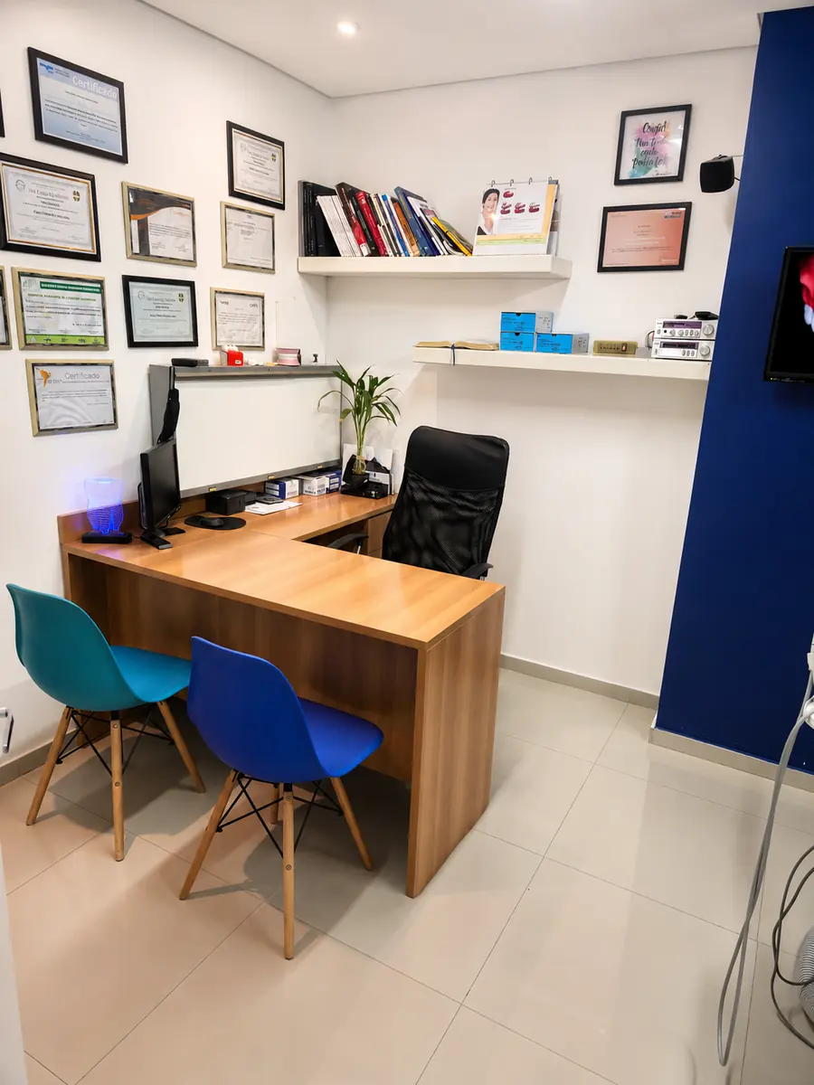 Sala de consulta do Dr. Danilo Menah com mesa, cadeiras e parede de certificados